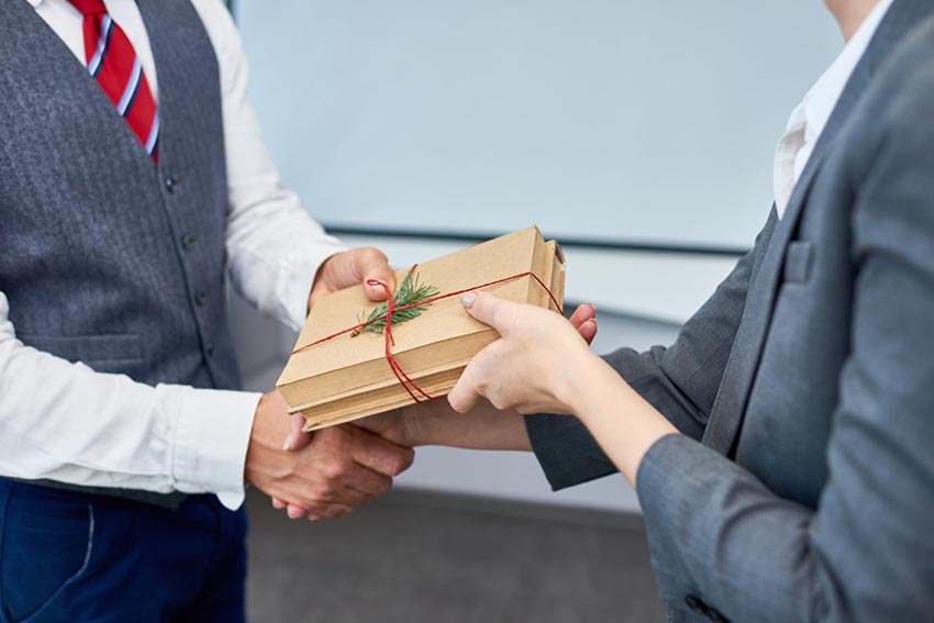 Muž a žena si medzi sebou vymieňajú darček zabalený v hnedom papieri