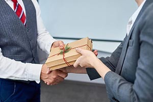 Obchodní partneri si medzi sebou vymieňajú pozornosť v podobe vianočného darčeka zabaleného v hnedom papieri