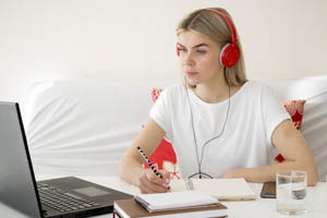 Študentka sediaca za notebookom so slúchadlami na ušiach
